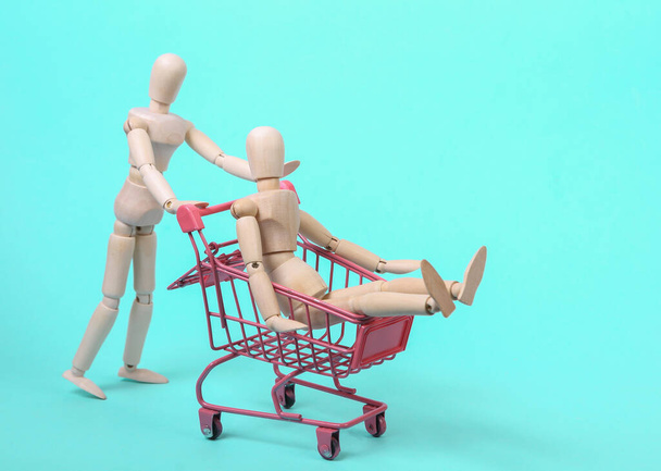 Ляльки з міні-торговим візком на синьому фоні. концепція шопінгу
 - Фото, зображення