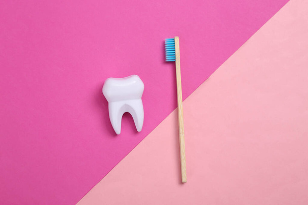 Eco-friendly bamboo and toothbrush and tooth on pink background. Dental care concept - Foto, Imagem