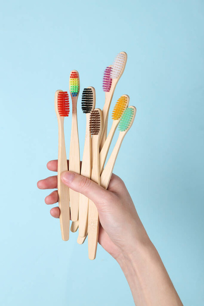 Hände, die umweltfreundliche Bambuszahnbürsten auf blauem Hintergrund halten. Zahnpflege. - Foto, Bild