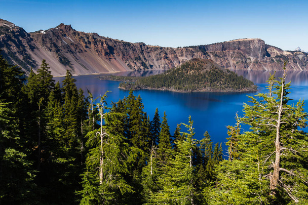 Hermosa perspectiva desde el borde del Parque Nacional del Lago del Cráter, con la isla maga contrastando con el agua azul profundo - Foto, Imagen