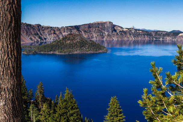 Belle perspective de la bordure du parc national du lac Crater, avec l'île de sorcier contrastant avec les eaux bleu profond - Photo, image