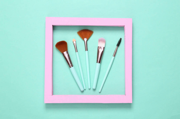 Make-up penselen met roze frame op blauwe achtergrond. Minimalismeindeling - Foto, afbeelding