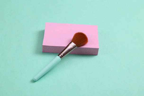 Minimalistic beauty scene. Makeup brush with pink platform on blue background.  - Foto, Imagem