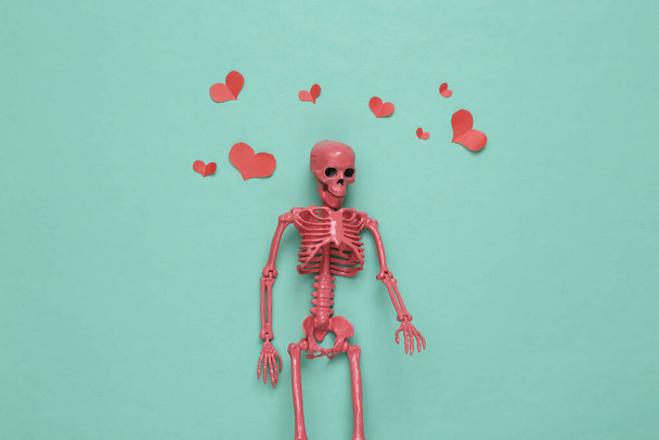 Ροζ σκελετός με καρδιές σε μπλε φόντο. Ρομαντικό, ερωτικό σκηνικό. Άνω όψη - Φωτογραφία, εικόνα
