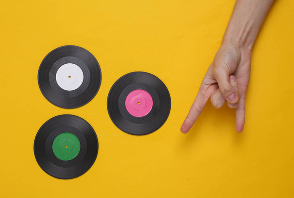 Vinyl δίσκους και το χέρι δείχνει Rock χειρονομία σε κίτρινο φόντο. Στο πάνω μέρος. Μινιμαλιστική μουσική έννοια. Ροκ εν Ρολ - Φωτογραφία, εικόνα