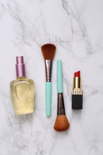 Makeup brushes, perfume bottle and lipstick on marble surface. Beauty products - Foto, Imagem
