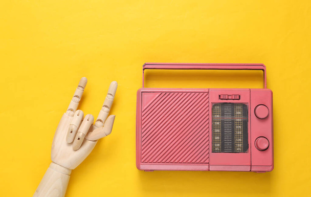 Radio Fm y mano de madera mostrando gesto Rock sobre fondo amarillo. Vista superior. Concepto de música minimalista. Rock'n'roll - Foto, imagen