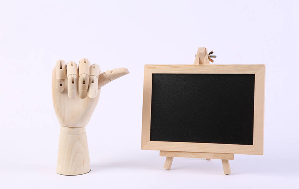 Wooden hand points with finger to empty chalk board on white background. Business or school concept - Photo, Image