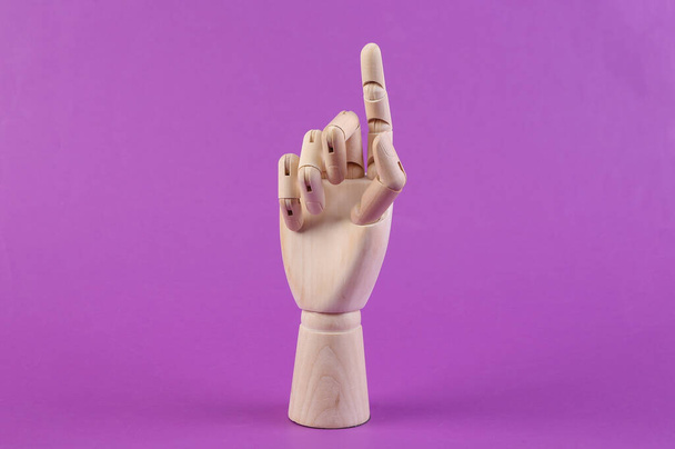 Muñeca de madera mano hacer dedos al tacto, directo. Fondo púrpura - Foto, imagen