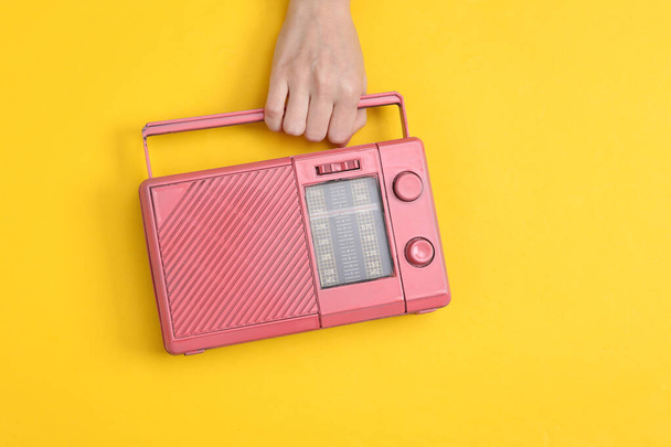 Жіноча рука тримає рожевий радіоприймач fm на жовтому тлі. Музика мінімальна концепція
 - Фото, зображення