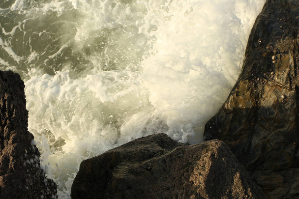 Atlantické vlny, valící se do zátoky Carlyon, smývají písek z pláže a dramaticky narážejí na skály po bouři u jižního pobřeží Anglie a okresu Cornwall. - Fotografie, Obrázek