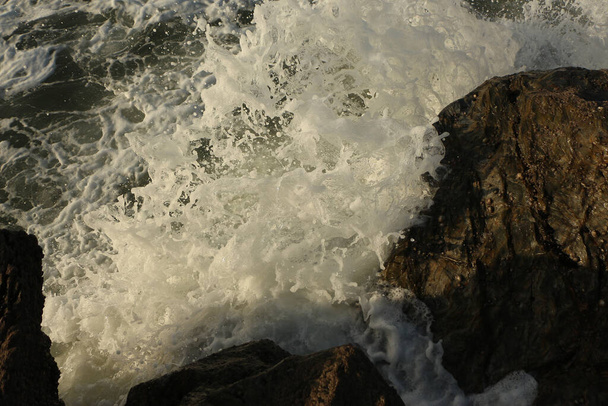 Atlantikwellen, die nach einem Sturm vor der Südküste Englands und der Grafschaft Cornwall in die Bucht von Carlyon schwappen und den Sand vom Strand wegspülen, stürzen dramatisch über die Felsen. - Foto, Bild