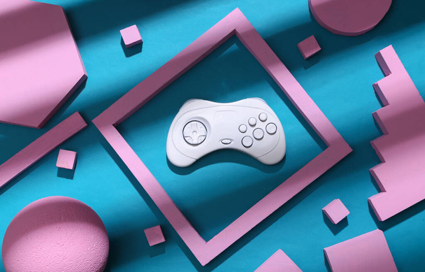 Witte gamepad met roze geometrische vormen op een blauwe achtergrond met trendy gestreepte schaduw. Creatieve indeling. Bovenaanzicht - Foto, afbeelding