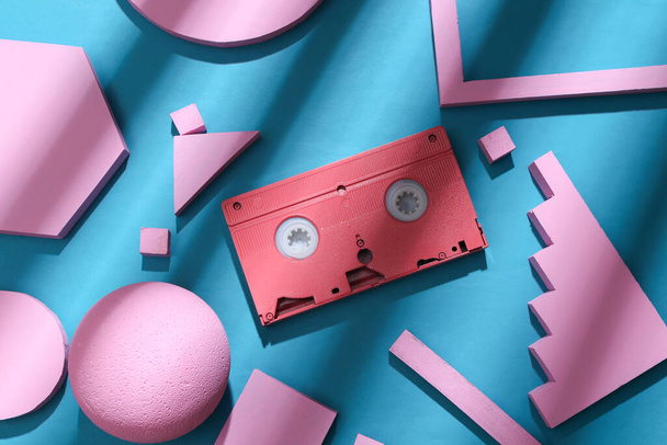 Pink video cassette with geometric shapes on a blue background with trendy striped shadow. Creative layout. Top view - Photo, Image