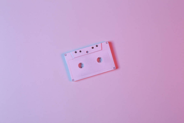Biała kaseta audio w różowo-niebieskim świetle neonowym. Koncepcja muzyki minimalistycznej  - Zdjęcie, obraz