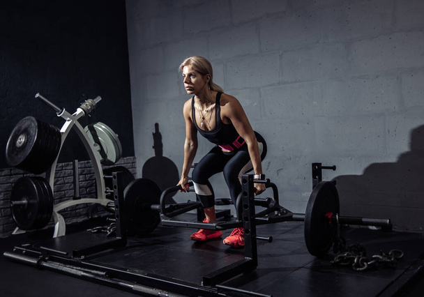 Vrouw die traint met zware gewichten in de sportschool. Fit vrouw doet deadlift workout met lange halter - Foto, afbeelding