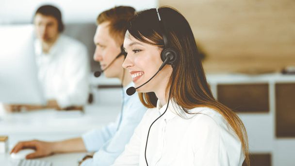 Group of diverse operators at work in call center. Beautiful asian woman sitting in headset at customer service office. Business concept - Photo, Image