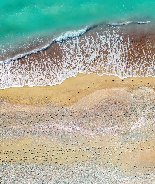 Human and dog footprints on a sandy shore along the sea with breaking waves, aerial vertical shot directly above - Photo, Image
