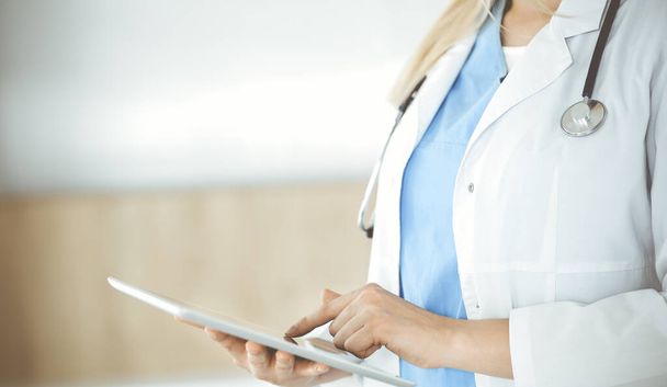 Unknown woman-doctor standing in clinic and using tablet pc, close-up. Data in medicine and healthcare - Φωτογραφία, εικόνα
