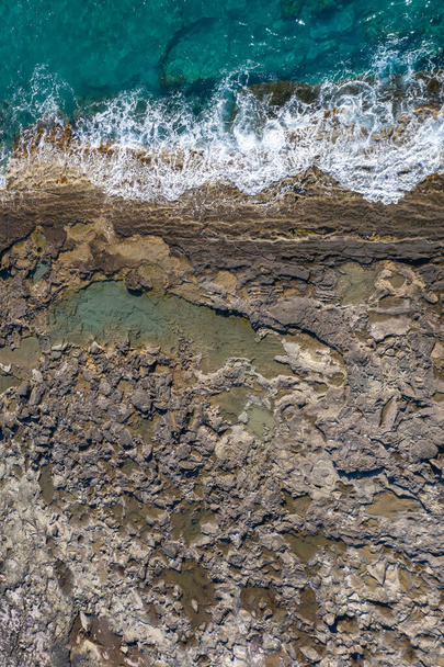 Tide pools during low tide. Rocky sea shore with dramatic texture, vertical top view - Photo, Image