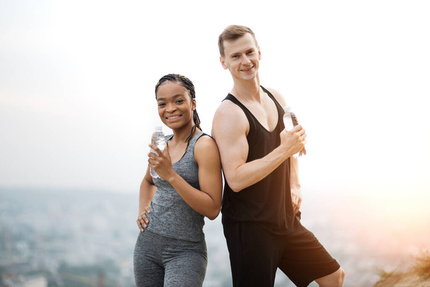 Sporty couple staning outdoors with bottle of water - Photo, image