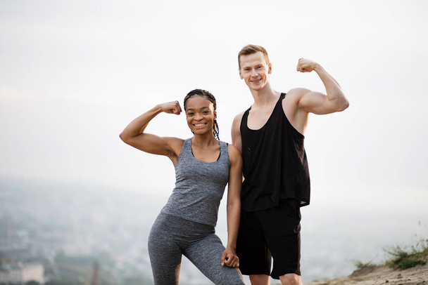 Smiling diverse couple showing their strong biceps - Fotó, kép