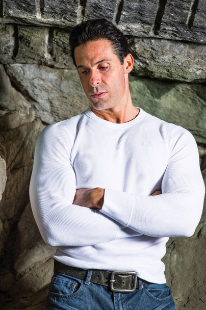 Одягаючись у білий светр, перетинаючи руки, чоловік середнього віку серйозно думає про стороннє
 - Фото, зображення