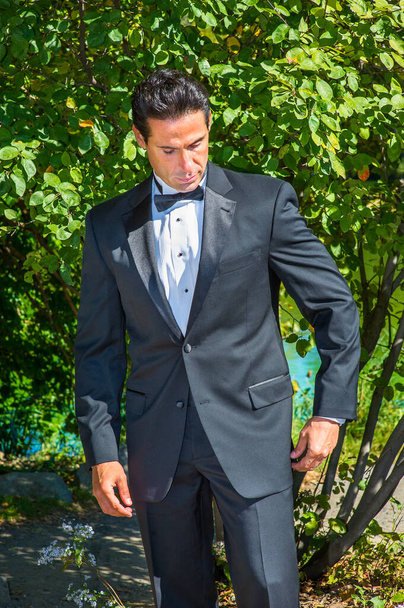 A professional executive is dressing in a black tuxedo, looking down and thinking - 写真・画像