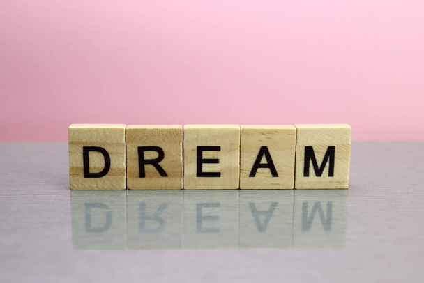 Dream word made of wooden letters on a pink background - Foto, imagen