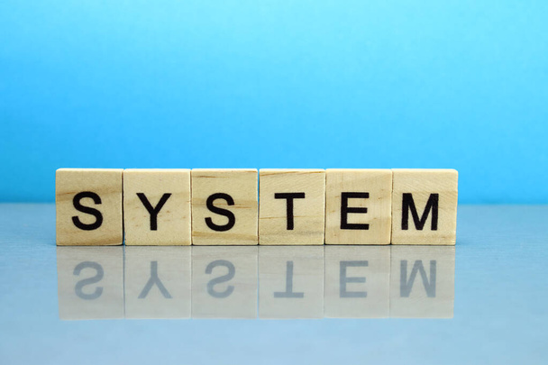 System word made of wooden blocks on a blue background - Foto, Imagem