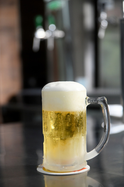 вкусная кружка супер холодного и освежающего пива на столе на размытом фоне - Фото, изображение