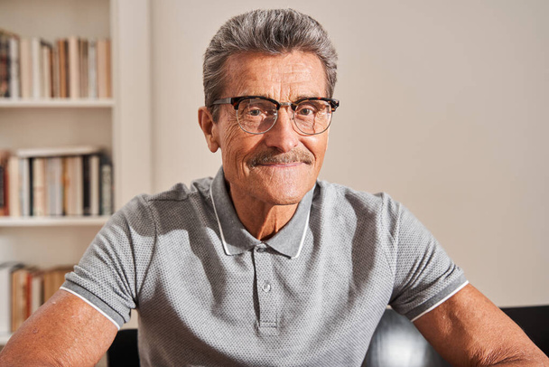 Man wearing glasses sharing positive emotions while posing to the camera - Fotografie, Obrázek