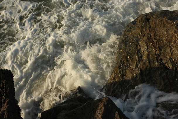 Atlantin aallot pyyhkäisevät Carlyonin lahdelle huuhtoen hiekan pois rannalta ja syöksyvät jyrkästi kallioiden yli myrskyssä Englannin etelärannikolla ja Cornwallin piirikunnassa. - Valokuva, kuva