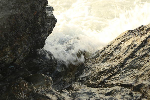キャリーオン湾に流れ込む大西洋の波が砂浜から砂を洗い流し、イングランドの南海岸とコーンウォール郡の嵐の後に劇的に岩を越えて墜落した。 - 写真・画像