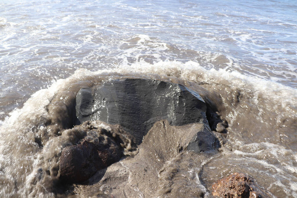 Хвилі розбиваються об чорний пісок і валуни на пляжі в Тенері. - Фото, зображення