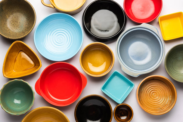 Colección de cuencos de cerámica de colores vacíos. Grupo de utensilios capturados desde arriba, vista superior, plano sobre fondo blanco - Foto, Imagen