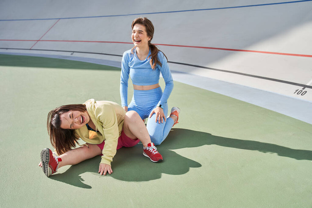 Midget woman stretching at the stadium while her best friend or trainer laughing out loud - Foto, imagen