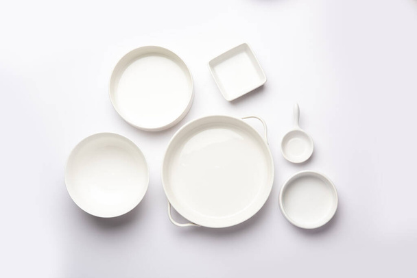Collection of empty colorful ceramic bowls. Group of utensils captured from above, top view, flat lay against white background - Foto, immagini