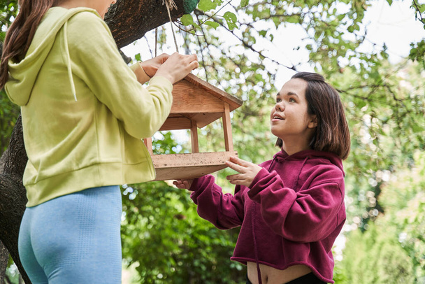 Midget woman chatting with her friend while keeping birds feeder at the tree - 写真・画像