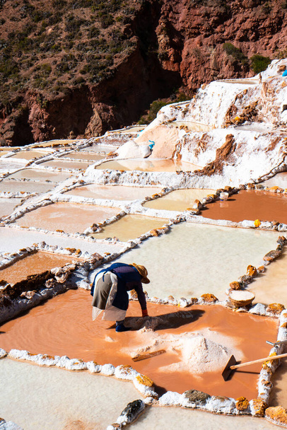 Werknemer in zoutterrassen van Maras in Cusco, Peru. Heilige vallei Andes.Artisan extractie. - Foto, afbeelding