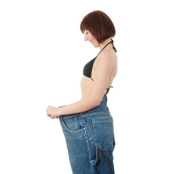 tiener vrouw laten zien hoeveel ze verloren gewicht - Foto, afbeelding