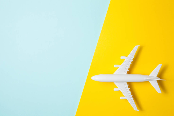 Flat lay design of travel concept with plane on yellow blue background with place for text. - Фото, изображение