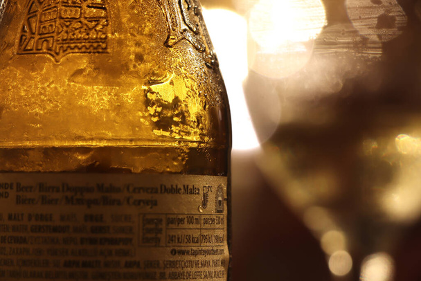 Beer bottle at night scattering light from nearby lamps - Photo, Image