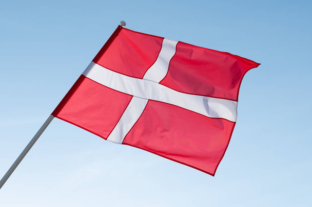 Deense vlag wapperend in de wind. Vlag van Denemarken op blauwe lucht achtergrond. - Foto, afbeelding