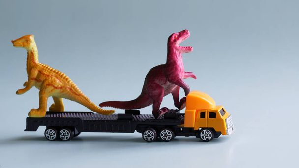 Іграшкова вантажівка має дві моделі динозаврів. Концепція перевезення незвичайних нестандартних вантажів та виконання найскладніших замовлень на доставку. Крупним планом
 - Фото, зображення