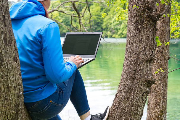 Nuori nainen, nainen freelancer työskentelee kannettavan kanssa Kaunis näkymä metsään ja järvelle. - Valokuva, kuva