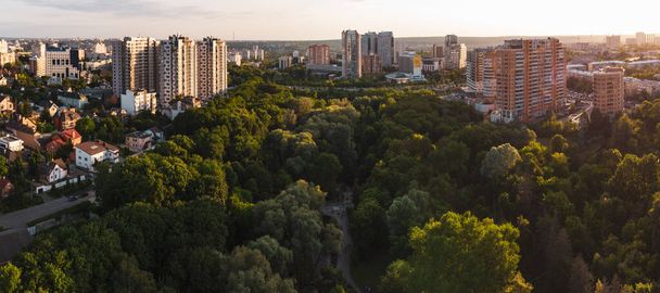 Aerial evening view on green summer Kharkiv city center popular recreation park Sarzhyn Yar. Botanical garden with water spring and playground in residential area in sunset light - Photo, image