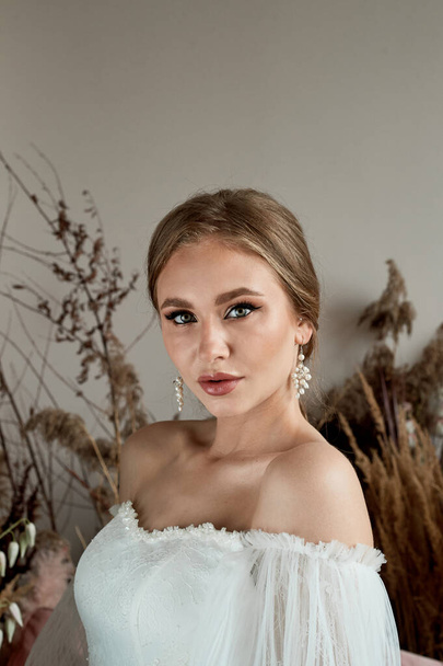 Portrait of the bride in a white dress with open shoulders. Tanned skin. Professional makeup. - Zdjęcie, obraz