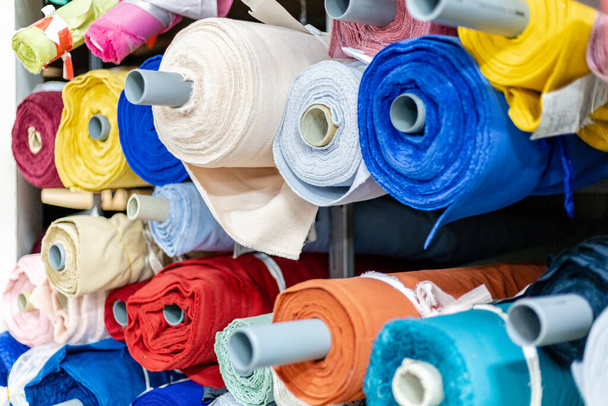 rolls of colored fabrics on a shelf in a warehouse - Фото, зображення