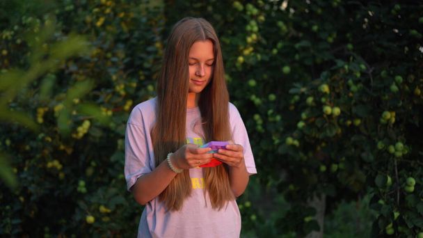 A girl with long hair plays popit in nature. Pop it is a popular silicone toy for children. - Φωτογραφία, εικόνα